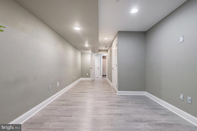 empty room featuring recessed lighting, baseboards, and light wood finished floors