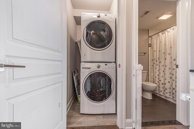 clothes washing area featuring stacked washer / drying machine, laundry area, tile patterned flooring, and visible vents