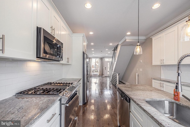 kitchen with stainless steel appliances, dark wood-type flooring, a sink, white cabinetry, and ornamental molding