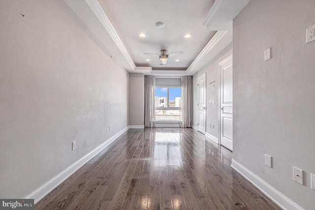 spare room featuring ornamental molding, baseboards, dark wood finished floors, and a raised ceiling