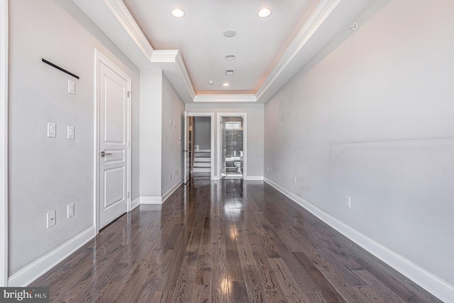 interior space featuring ornamental molding, a tray ceiling, baseboards, and wood finished floors