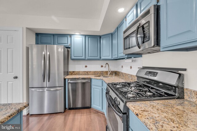 kitchen with a sink, blue cabinetry, and stainless steel appliances