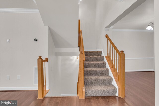 stairway featuring visible vents, baseboards, wood finished floors, and ornamental molding