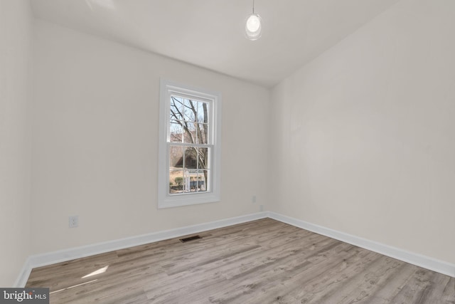 empty room with visible vents, baseboards, and wood finished floors