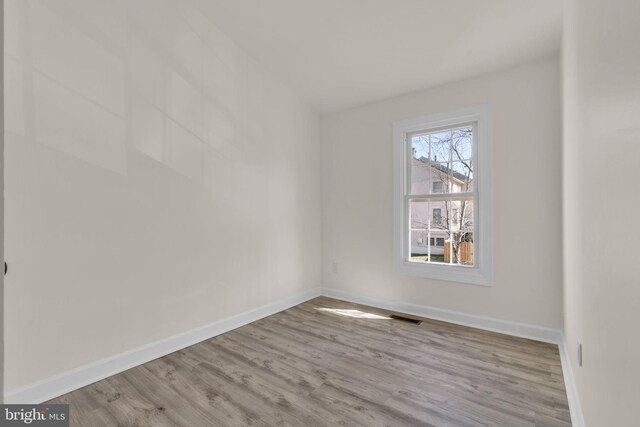 empty room with visible vents, baseboards, and wood finished floors