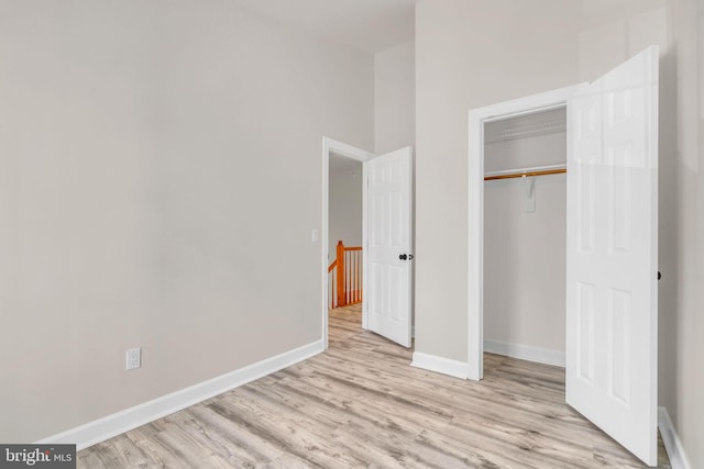unfurnished bedroom featuring a closet, baseboards, and wood finished floors