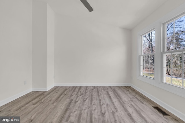 empty room featuring plenty of natural light, wood finished floors, and visible vents