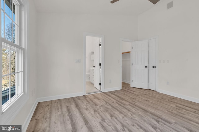 unfurnished bedroom featuring connected bathroom, visible vents, baseboards, and wood finished floors