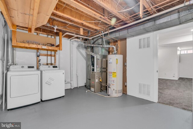 unfinished below grade area featuring heating unit, visible vents, gas water heater, and washer and dryer