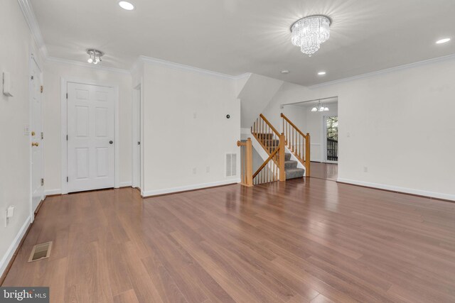 unfurnished room with stairs, a notable chandelier, wood finished floors, and visible vents