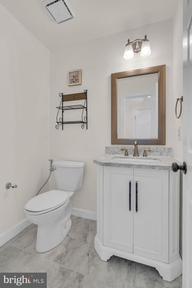 bathroom featuring baseboards, toilet, marble finish floor, and vanity