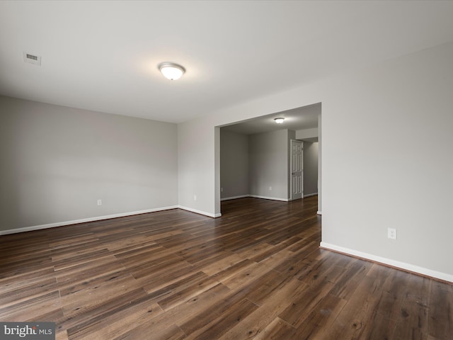 empty room featuring baseboards, visible vents, and dark wood finished floors