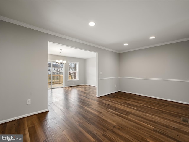 spare room featuring dark wood-style floors, ornamental molding, baseboards, and an inviting chandelier