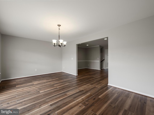 unfurnished dining area with a notable chandelier, baseboards, and dark wood-type flooring