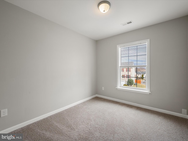 unfurnished room with carpet, visible vents, and baseboards