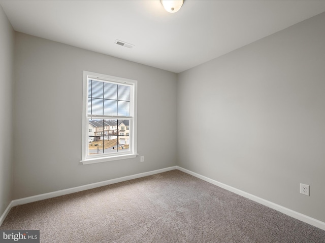 carpeted spare room featuring visible vents and baseboards