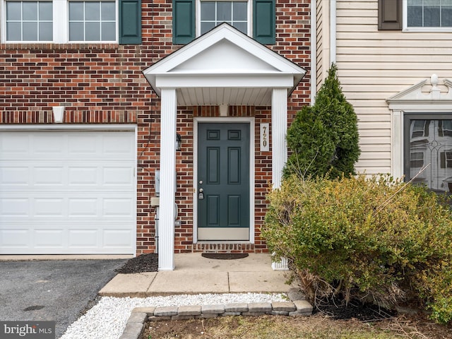 property entrance featuring a garage and brick siding