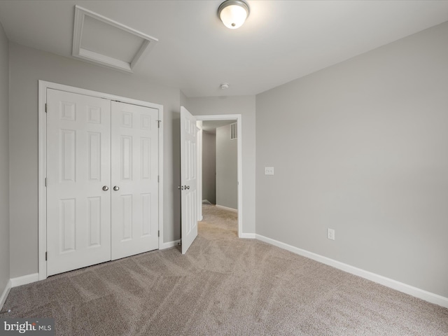 unfurnished bedroom with carpet floors, visible vents, baseboards, a closet, and attic access