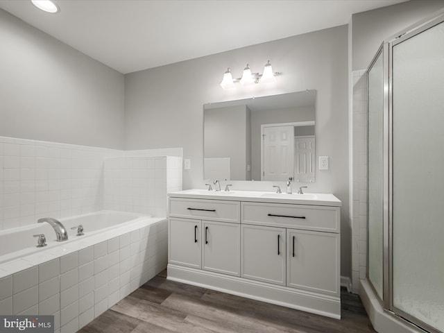 bathroom with wood finished floors, a sink, a bath, and a shower stall