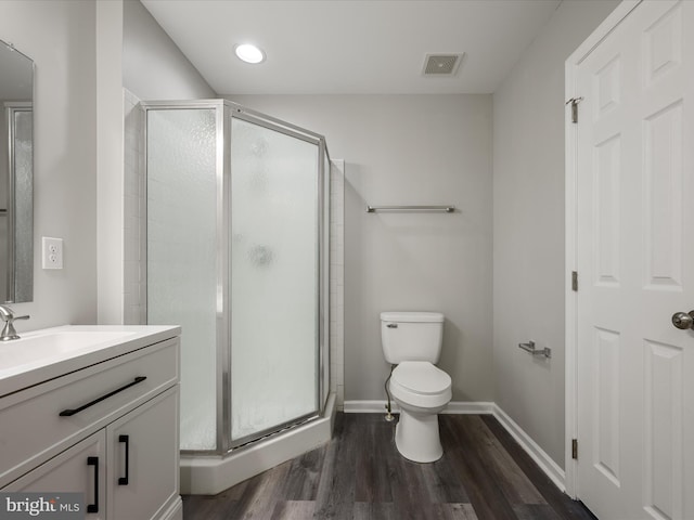 bathroom with toilet, wood finished floors, vanity, visible vents, and a stall shower