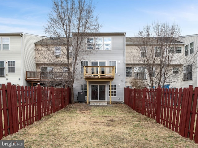 rear view of house with cooling unit, a fenced backyard, and a yard