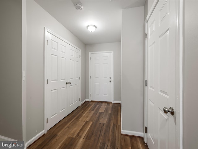 corridor featuring baseboards and dark wood-type flooring