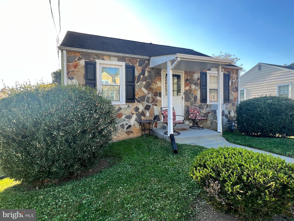 view of front facade with stone siding and a front lawn