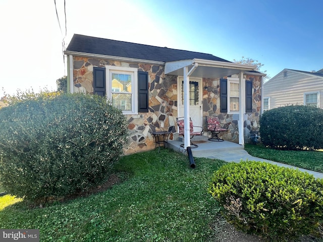 view of front facade with stone siding and a front lawn