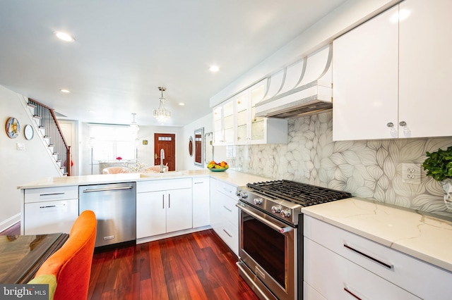 kitchen featuring appliances with stainless steel finishes, dark wood-type flooring, a peninsula, extractor fan, and a sink