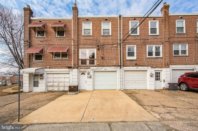 view of front of property with driveway, a garage, central AC, and brick siding