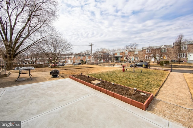 view of property's community featuring an outdoor fire pit, a residential view, and a lawn