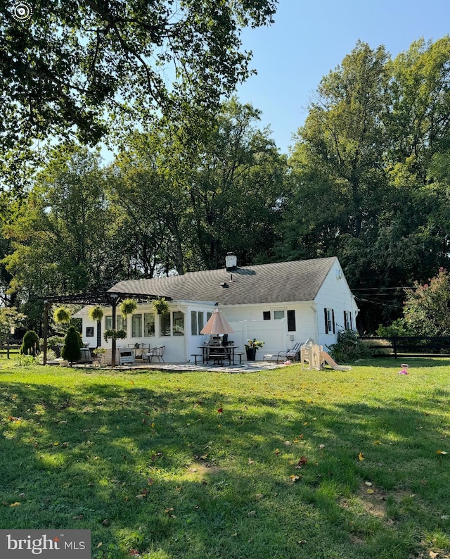 back of property with a yard and a patio area