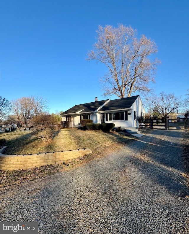 view of front of property with a chimney, gravel driveway, and fence