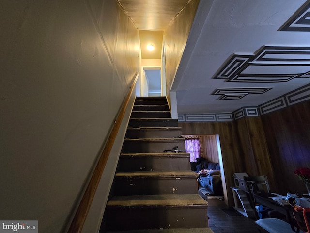 stairway featuring wooden walls and wood finished floors