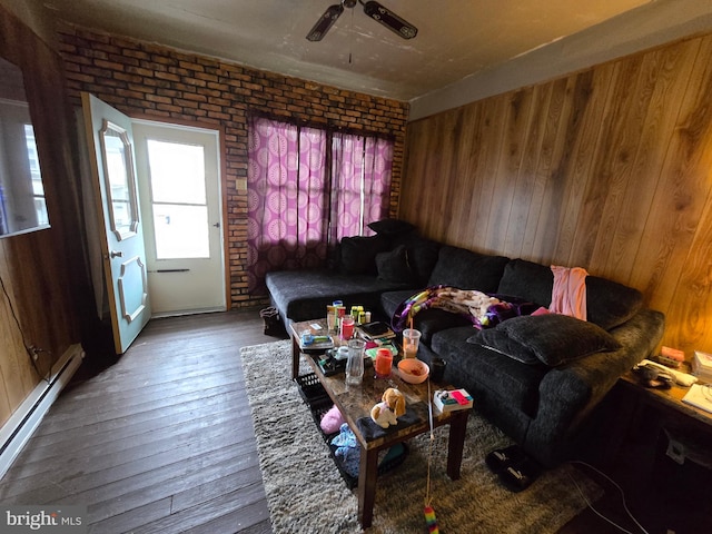 living room with a baseboard heating unit, wood-type flooring, wood walls, and brick wall