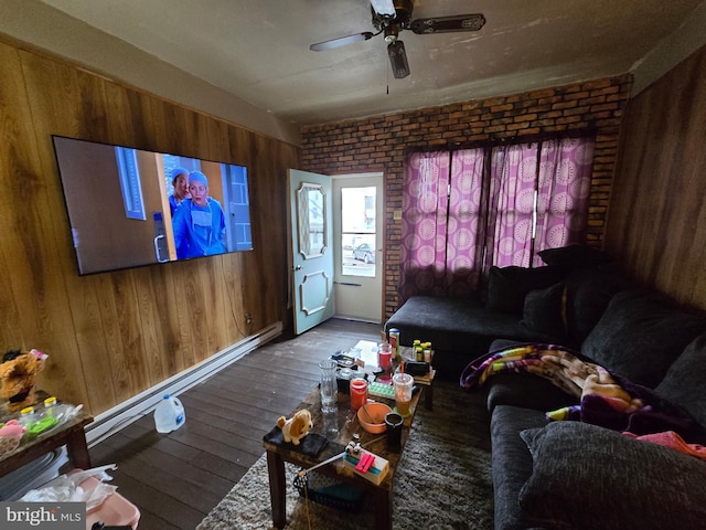 living area featuring a ceiling fan, brick wall, hardwood / wood-style floors, baseboard heating, and wood walls