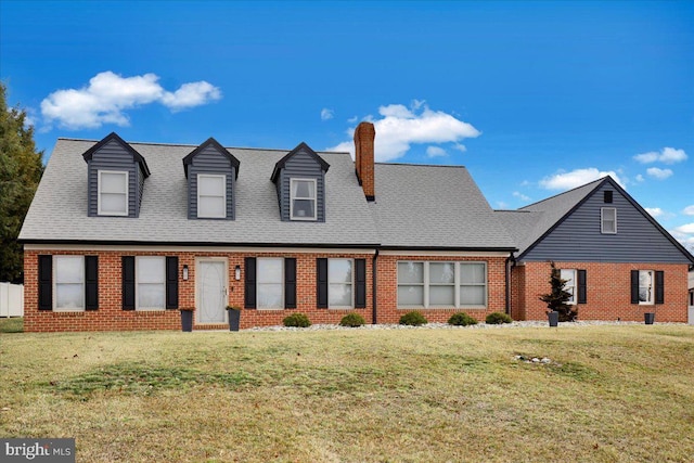 cape cod-style house with roof with shingles, a chimney, a front lawn, and brick siding