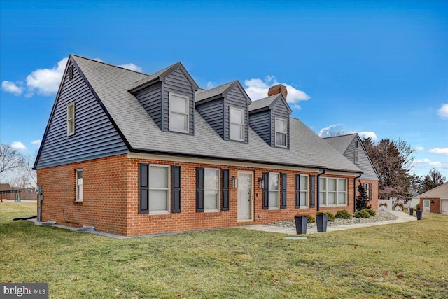 exterior space with brick siding, a chimney, a front yard, and a shingled roof