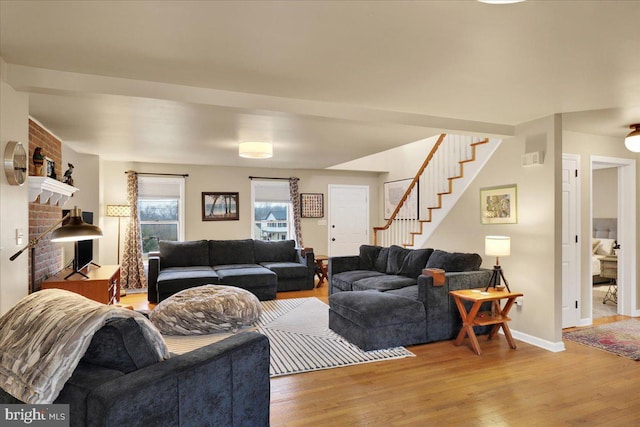 living room with stairs, light wood finished floors, and baseboards