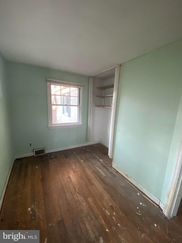 unfurnished bedroom with wood-type flooring, visible vents, and baseboards