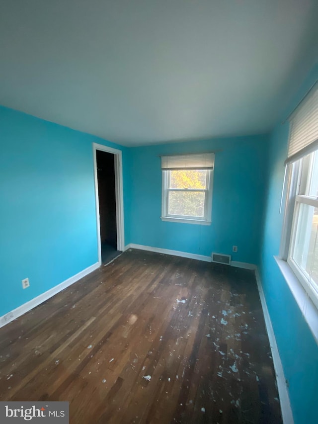 unfurnished room featuring baseboards, visible vents, and wood finished floors