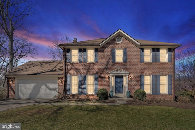 colonial house with driveway, brick siding, a front lawn, and an attached garage