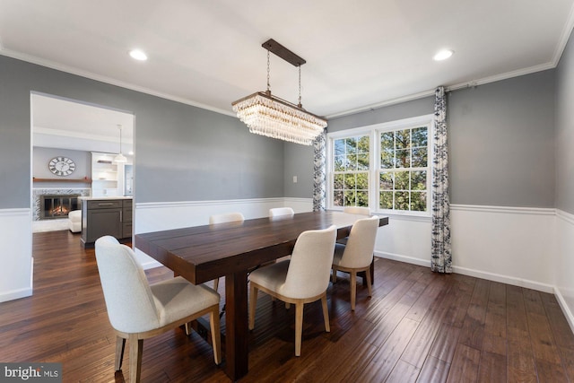 dining room featuring ornamental molding, dark wood-style flooring, a glass covered fireplace, and recessed lighting