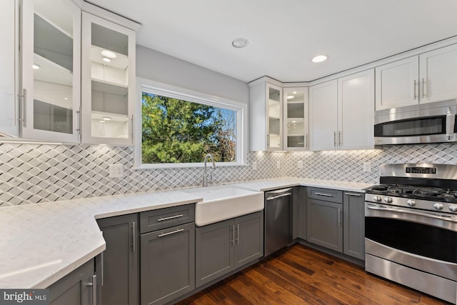 kitchen with a sink, white cabinetry, appliances with stainless steel finishes, gray cabinets, and backsplash