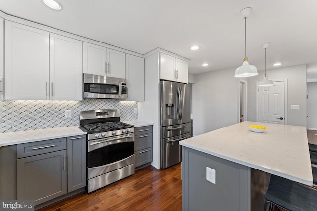 kitchen featuring dark wood-style floors, light stone countertops, gray cabinets, stainless steel appliances, and backsplash