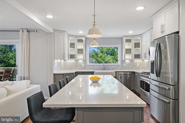 kitchen featuring stainless steel appliances, a breakfast bar, glass insert cabinets, and backsplash