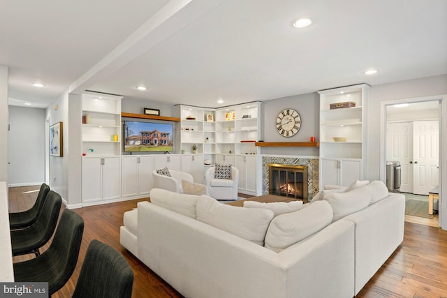 living room with built in shelves, a high end fireplace, hardwood / wood-style flooring, and recessed lighting