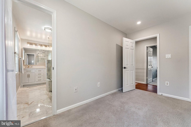 unfurnished bedroom featuring baseboards, recessed lighting, ensuite bathroom, and light colored carpet