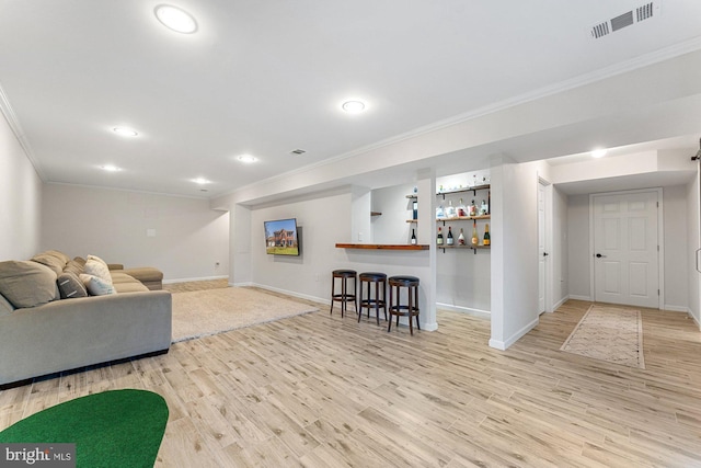 living area featuring baseboards, visible vents, ornamental molding, wood finished floors, and a bar