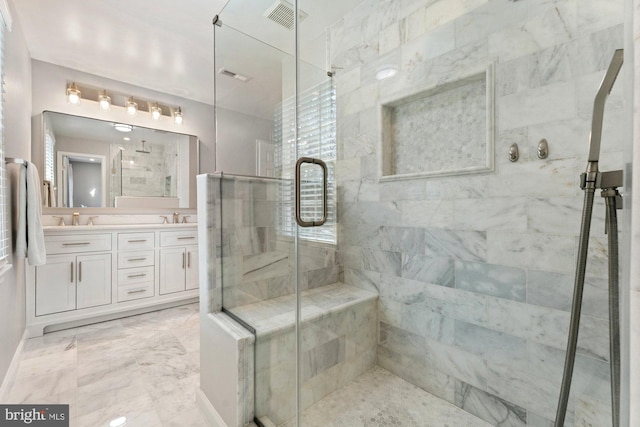 full bathroom featuring marble finish floor, a stall shower, and a sink